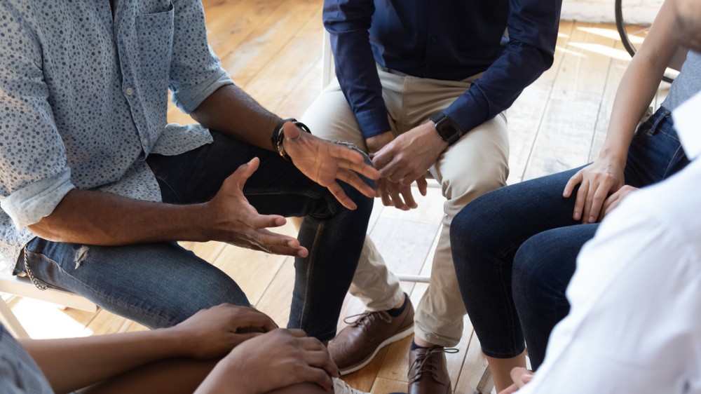 A group in counselling session together, pictured from the neck down