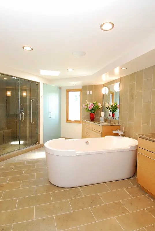 Modern primary bath free-staning tub over tile flooring.Modern kitchen with wooden cabinets, central island, hanging lights, and dark flooring. Irvine Transitional Modern. Photo by Chris Darnall.