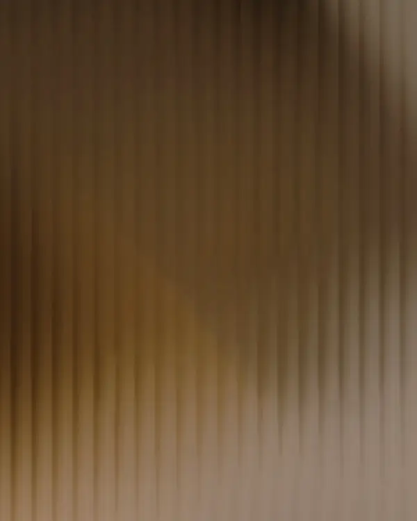 Abstraktní pozadí s texturou v teplých zemitých tónech a hrou světla, navozující pocit stability, důstojnosti a naděje.