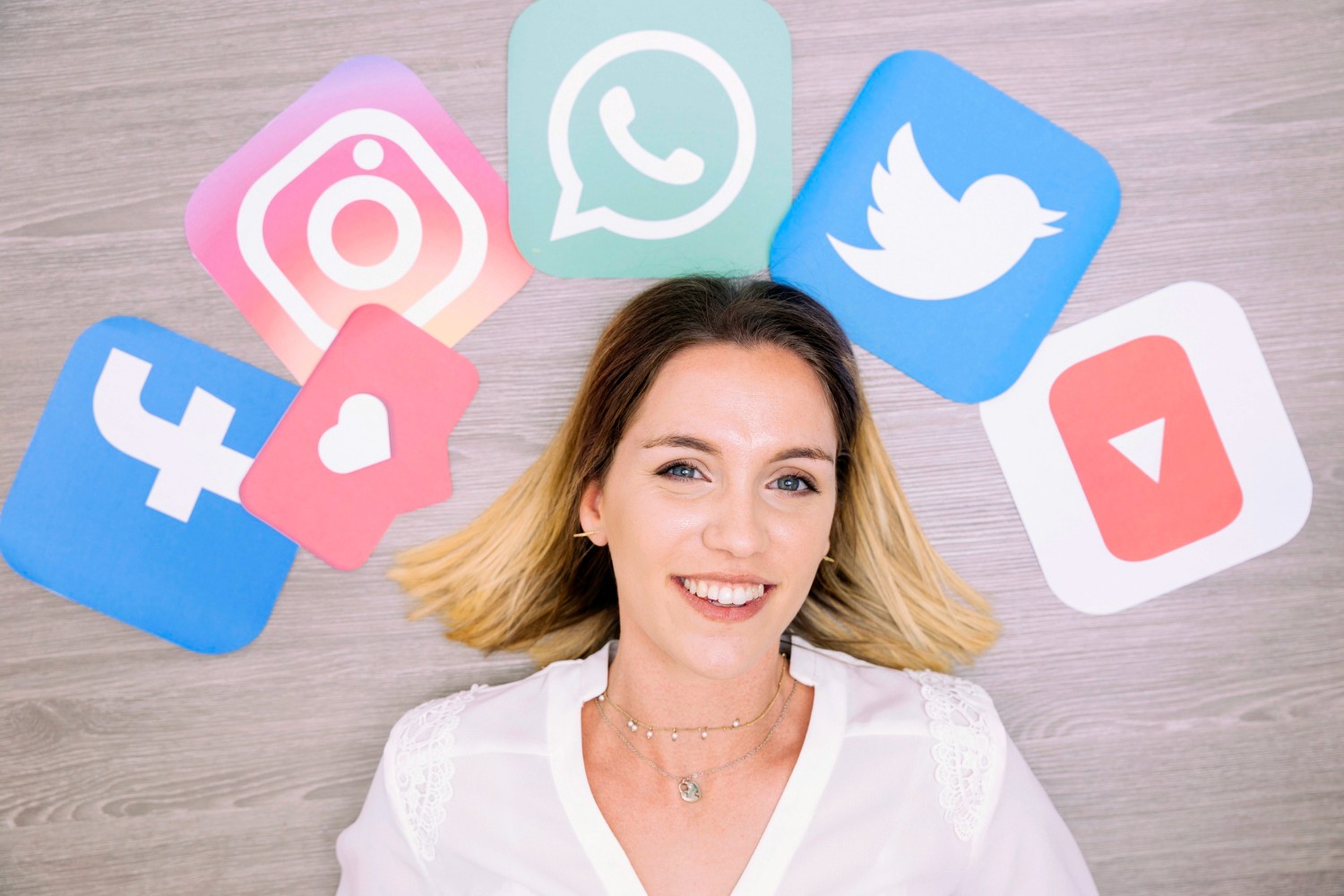  A woman smiling joyfully, surrounded by various social media icons, symbolizing connection and engagement online.