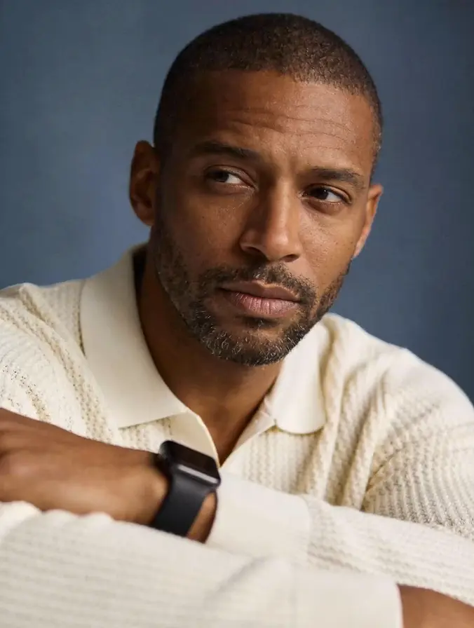 Close-up portrait of a man in a light shirt looking down thoughtfully