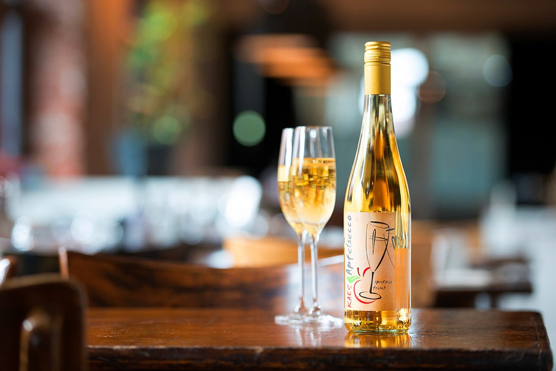 A stylish green armchair next to a modern lamp, set against a dark wall for a cozy atmosphere.