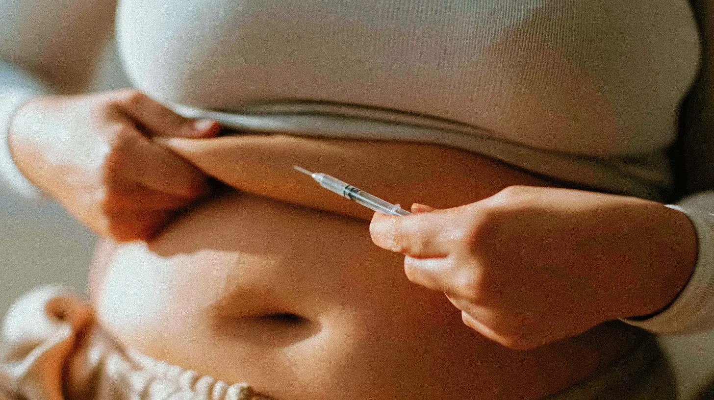 A close-up of a person's midsection receiving a GLP-1 injection into the abdomen.