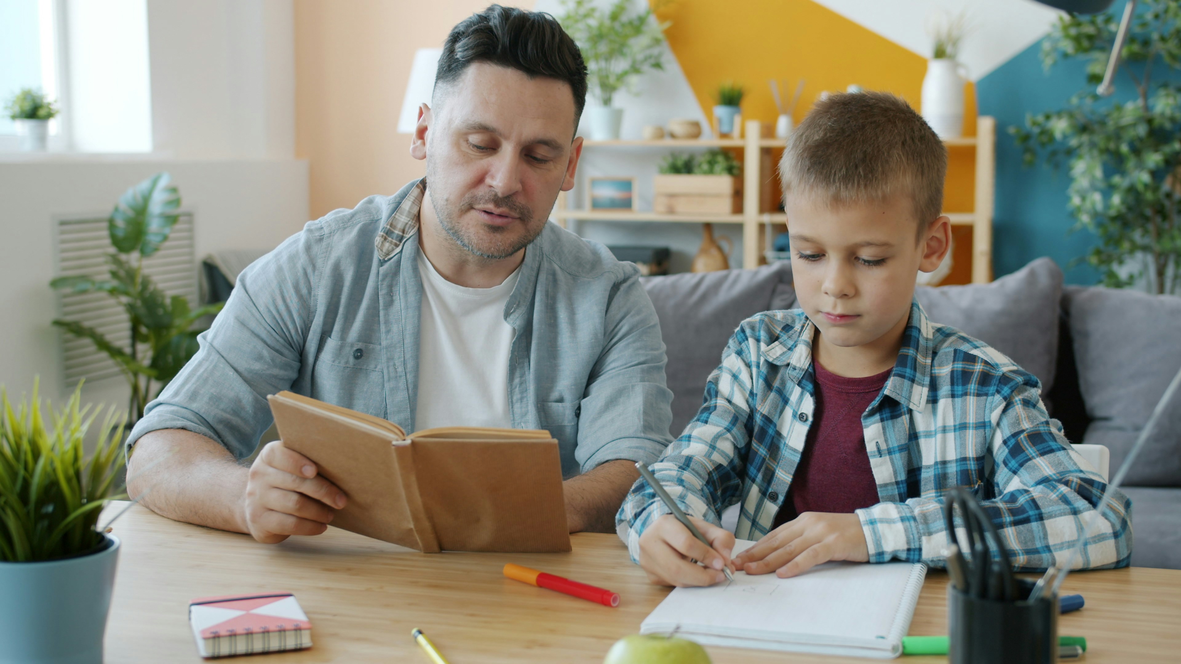 Father and son reading and writing at table