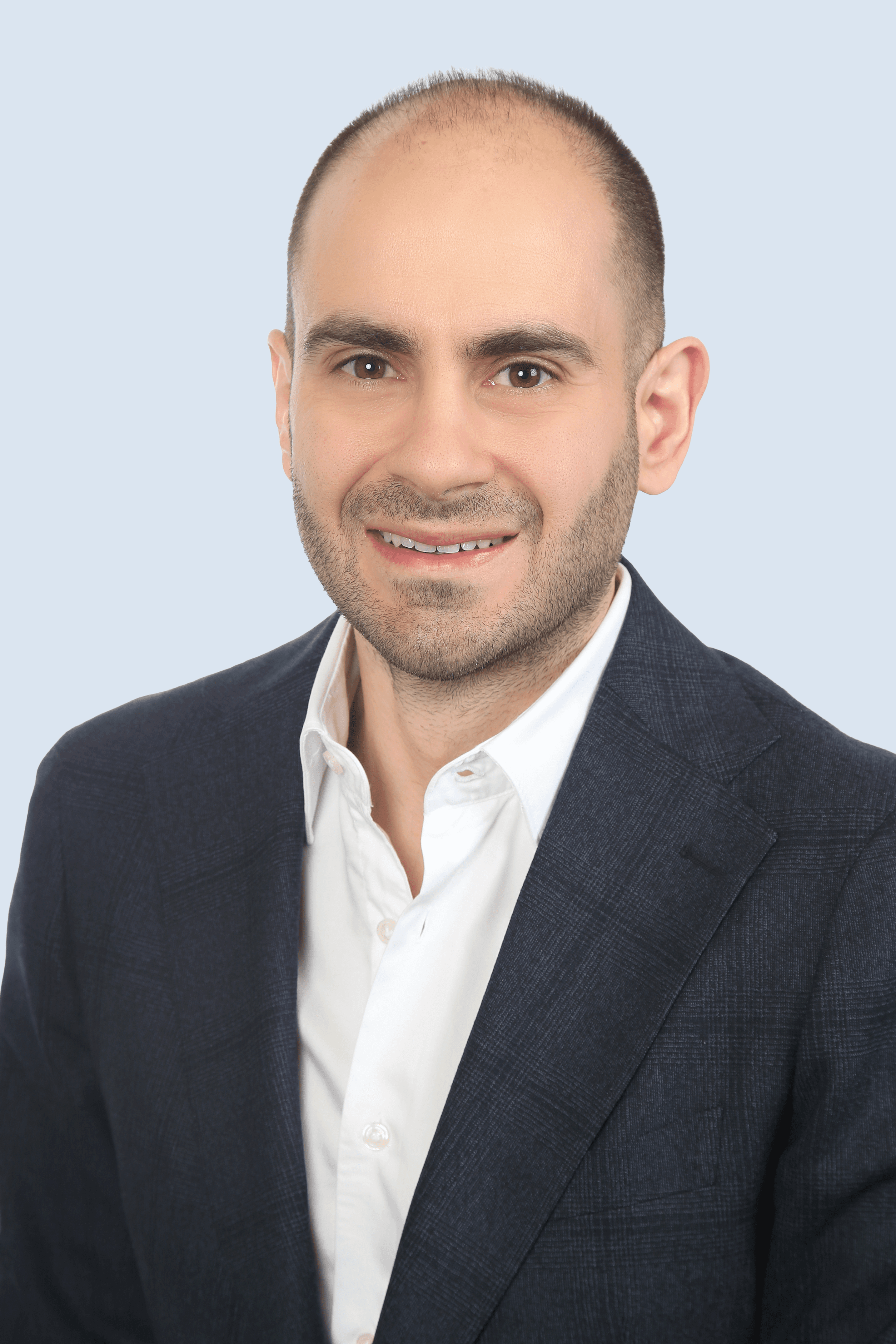 Ein Mann mit schwarzem Sack und weißem Hemd lächelt zuversichtlich in die Kamera.