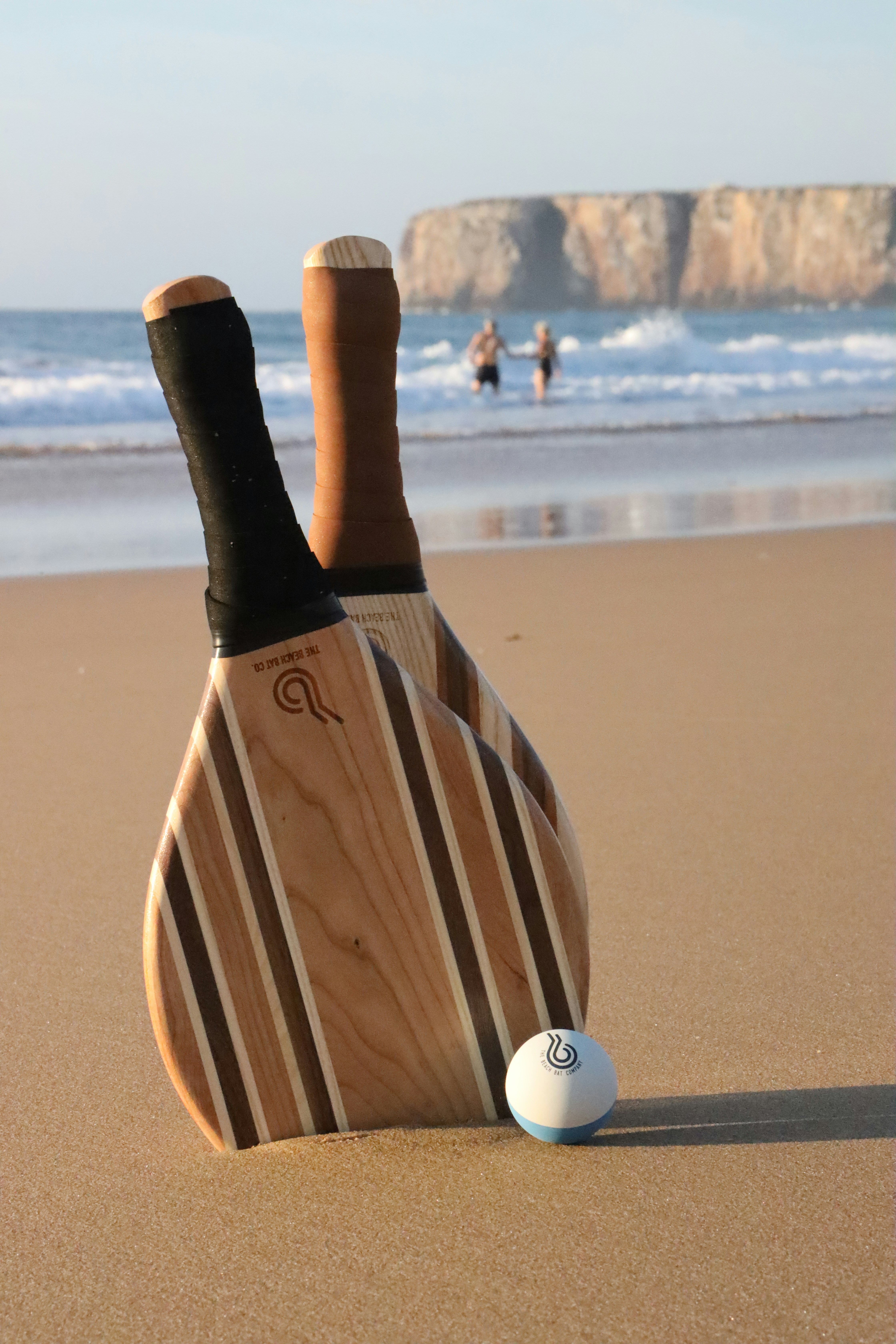 a wooden paddle and a ball on a beach