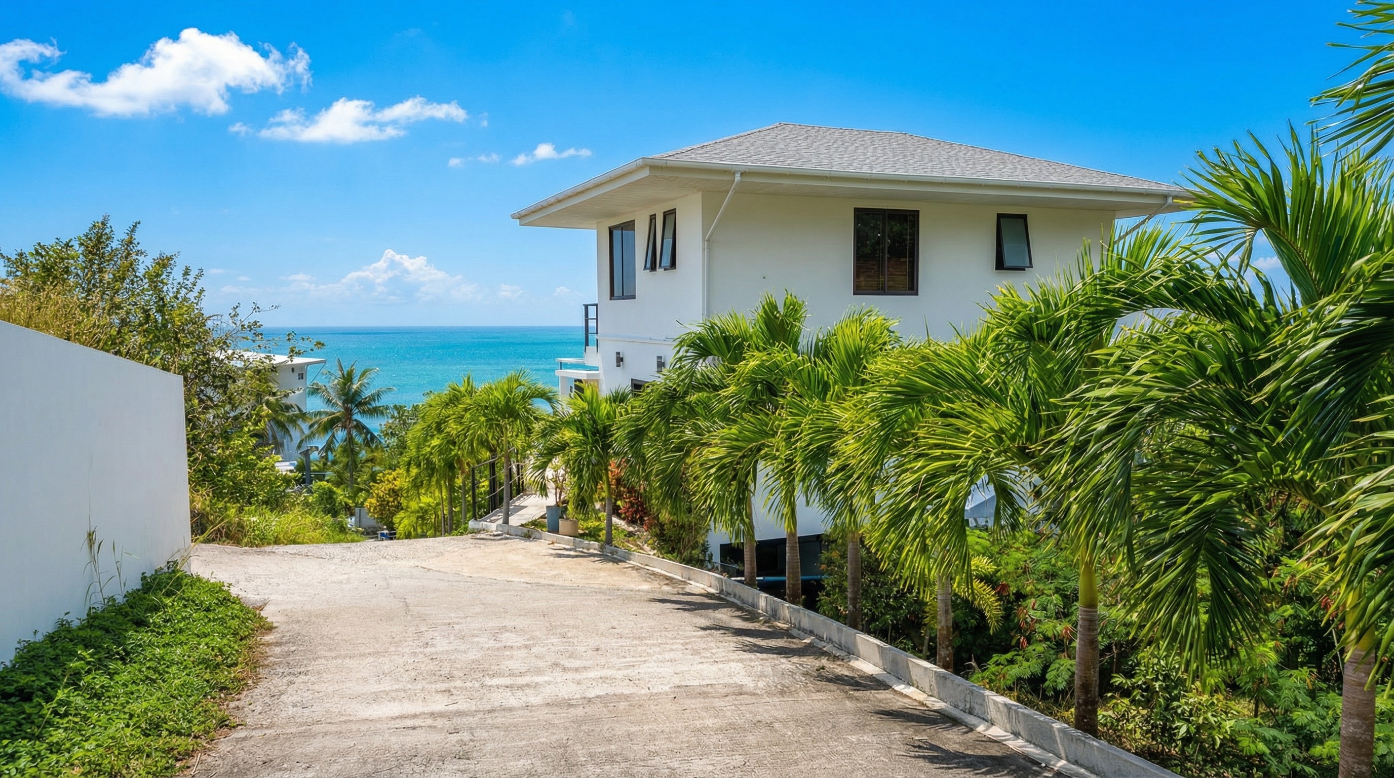 Outdoor lounge under a wooden pergola, draped linen curtains, beige cushions, ocean backdrop, palm shadows dancing on the walls, serene luxury.