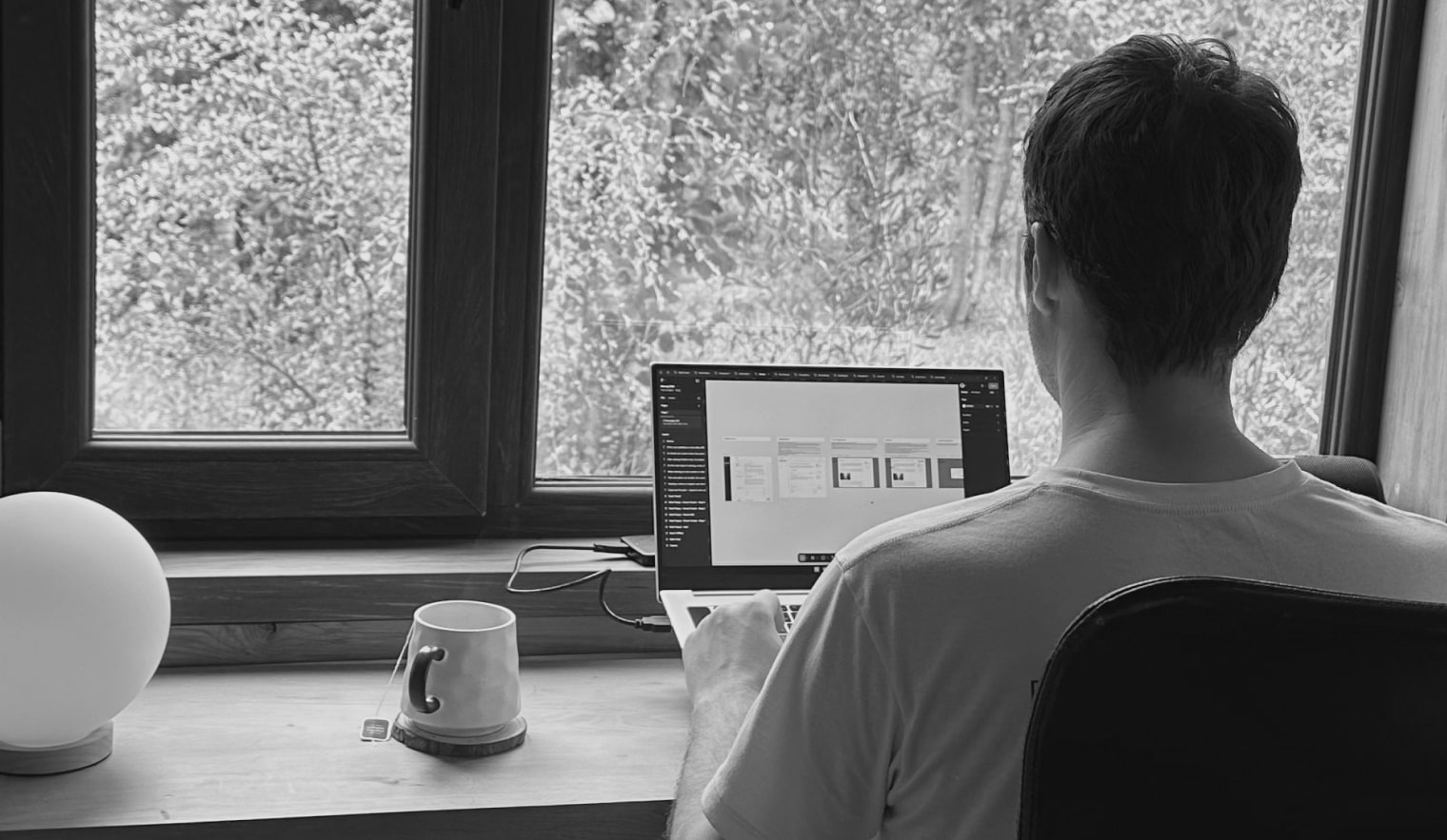 Black and white image of people working at a table with laptops, showing hands gesturing during discussion of digital content displayed on screens, with fabrica® logo in the corner.