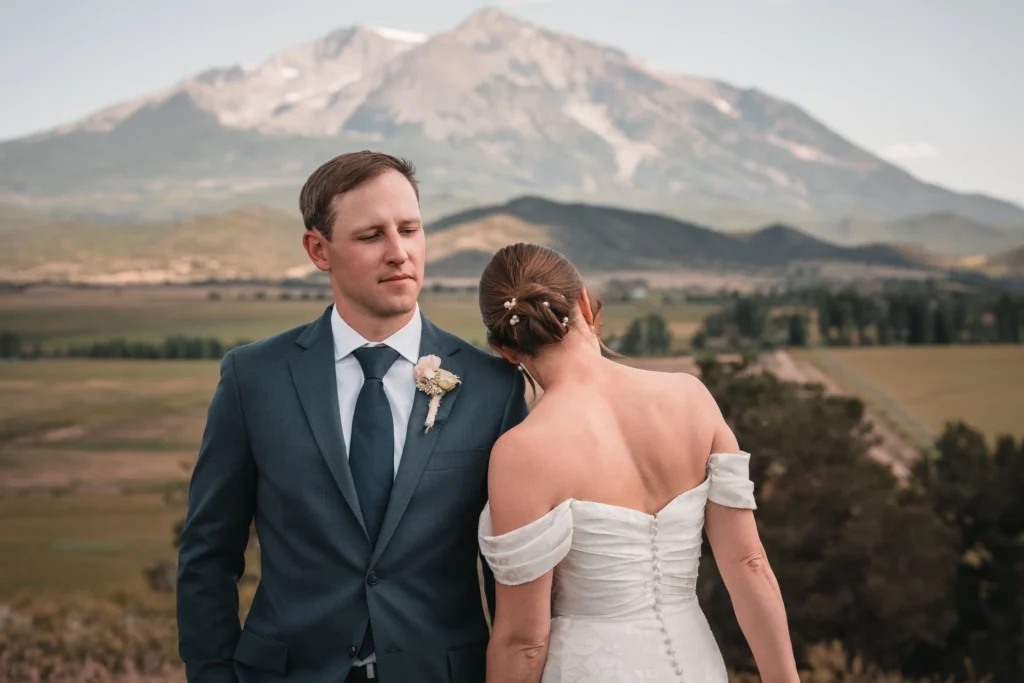 Newlyweds standing face-to-face above a broad valley