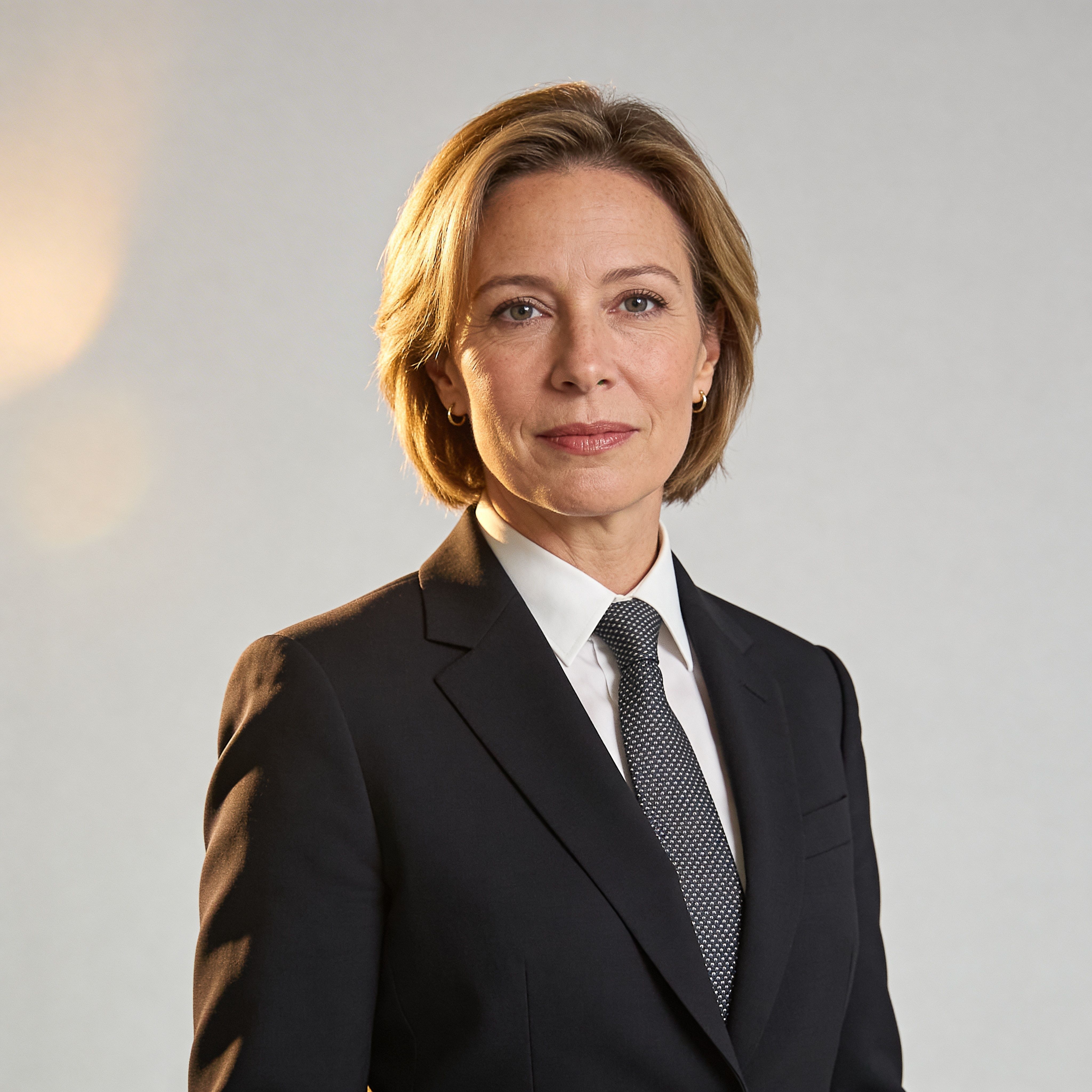 Professional woman in a black suit with short hair, neutral expression and strong executive presence