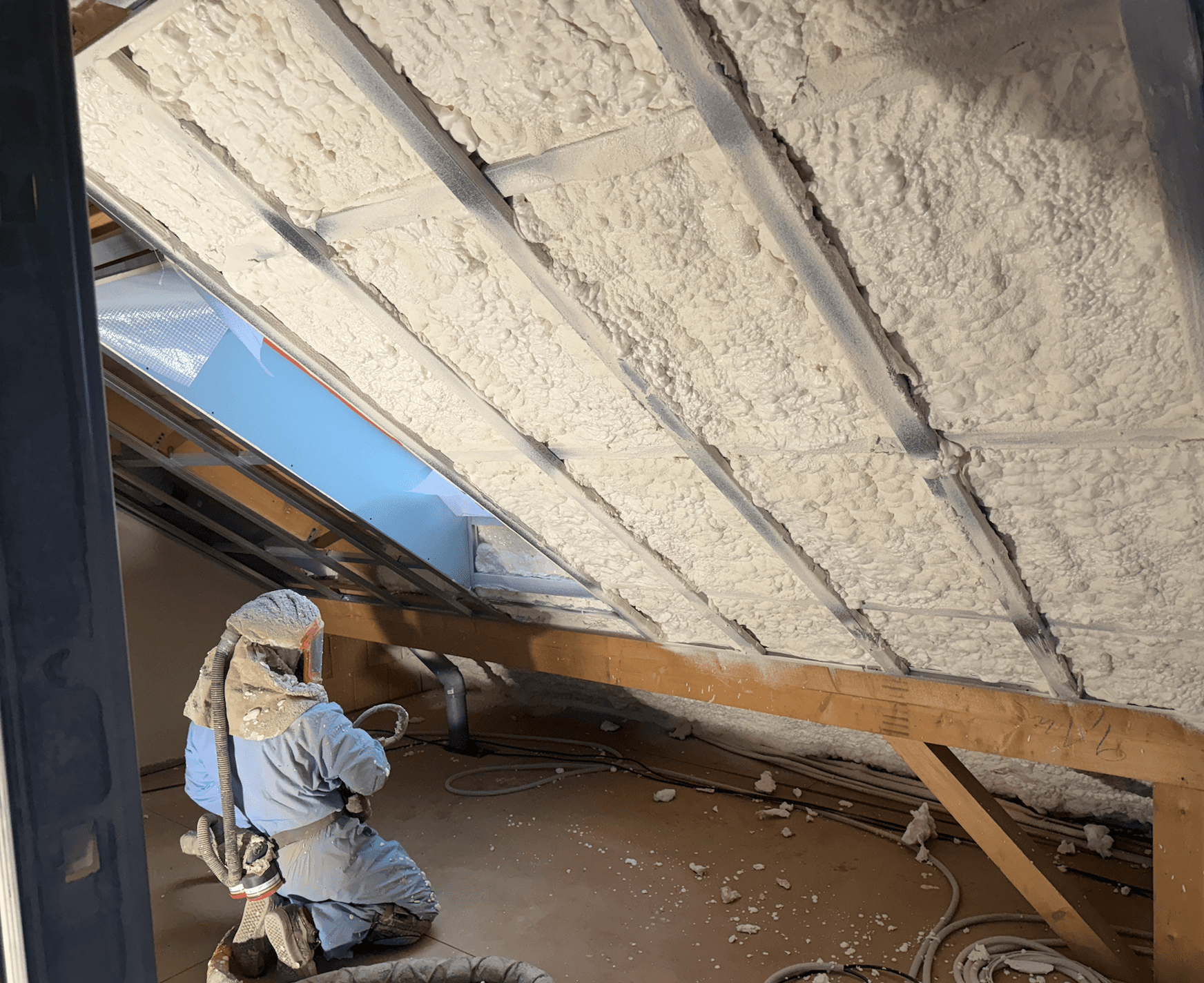 A smiling woman with her arms crossed, standing against a dark green background. She has long, dark hair.