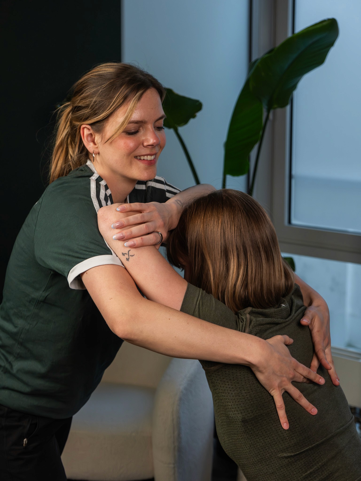 Eine Physiotherapeutin dehnt die Schulter einer Patientin.