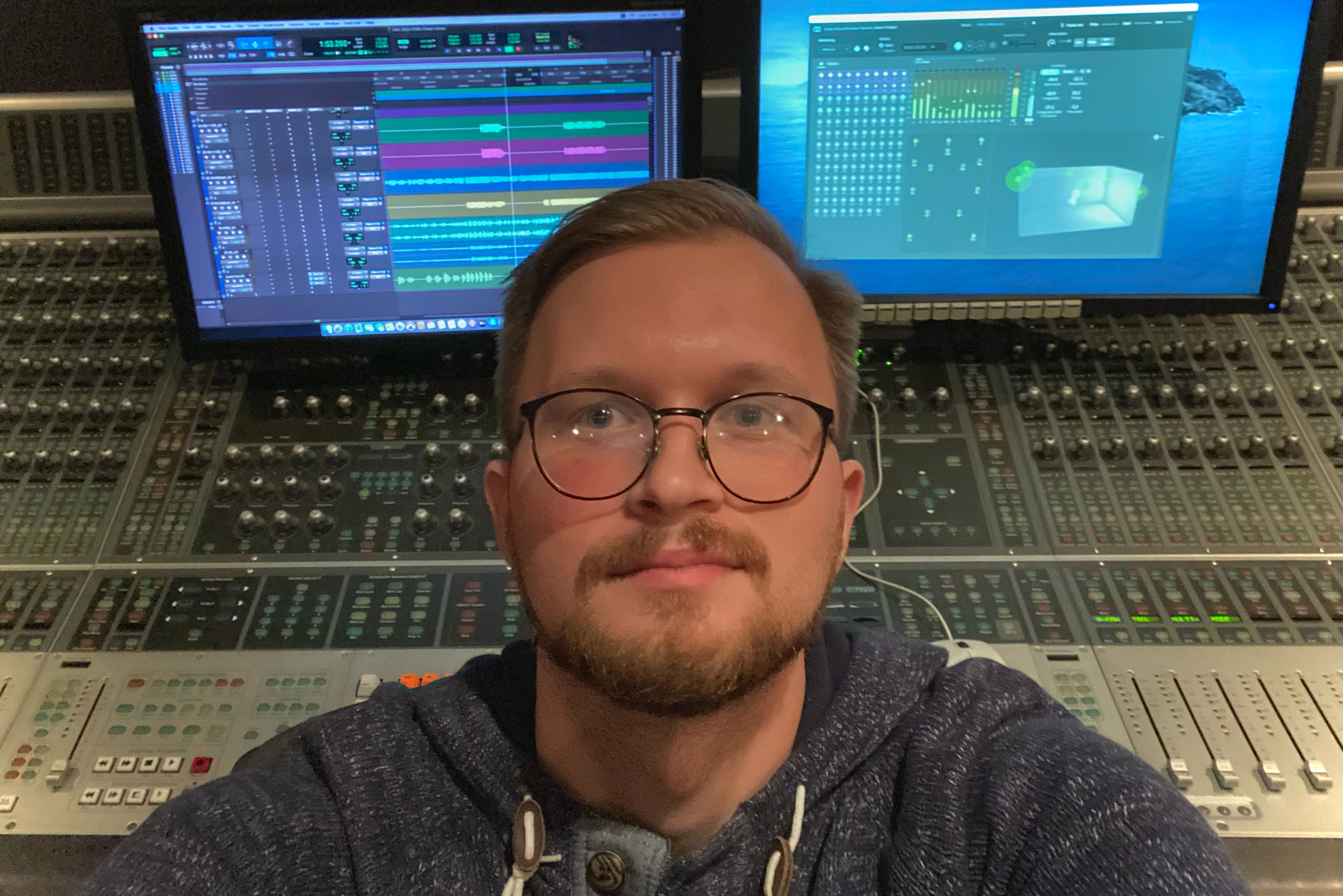 A personal photo of owner of GK Mixing with a professional mixing console and Dolby Atmos studio setup featuring dual monitors displaying a digital audio workstation (DAW) interface and surround sound panning tools, highlighting a state-of-the-art environment for precise music mixing and mastering.