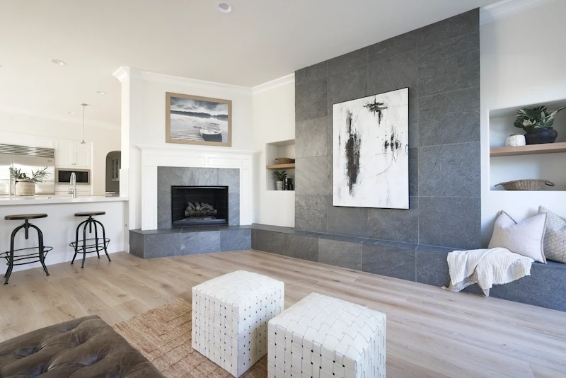 Spacious living area with fireplace, textured gray wall, and open kitchen view in Bonita Canyon Remodel.