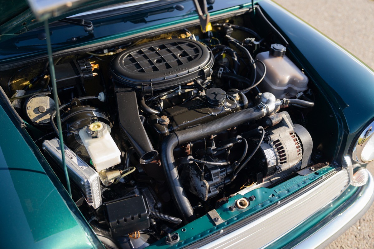 Close-up of a car engine, featuring various components in a teal engine bay with a focus on mechanical details.