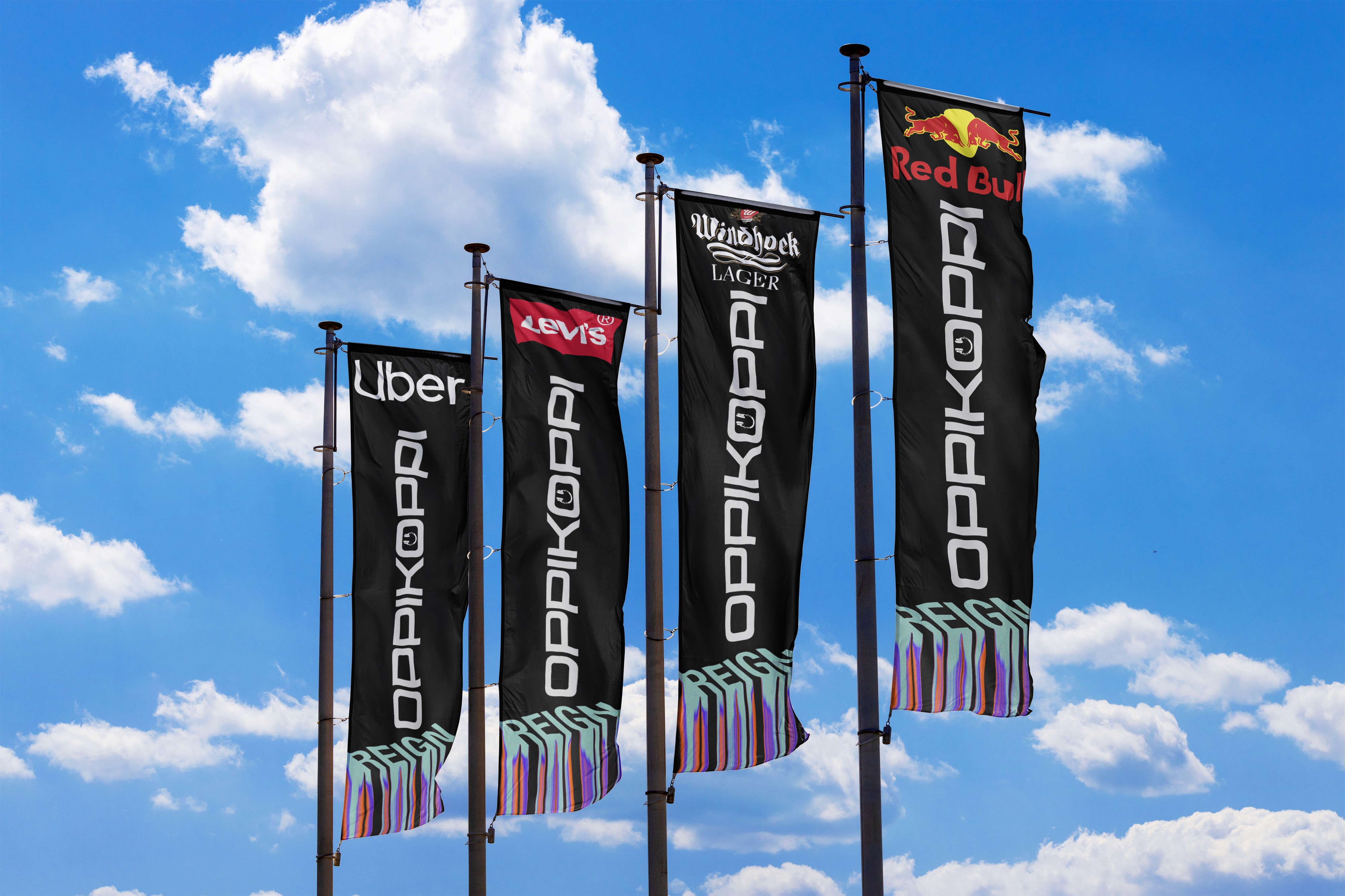 Row of tall black outdoor event advertising banners featuring bold custom festival typography standing against a bright blue sky with white clouds.