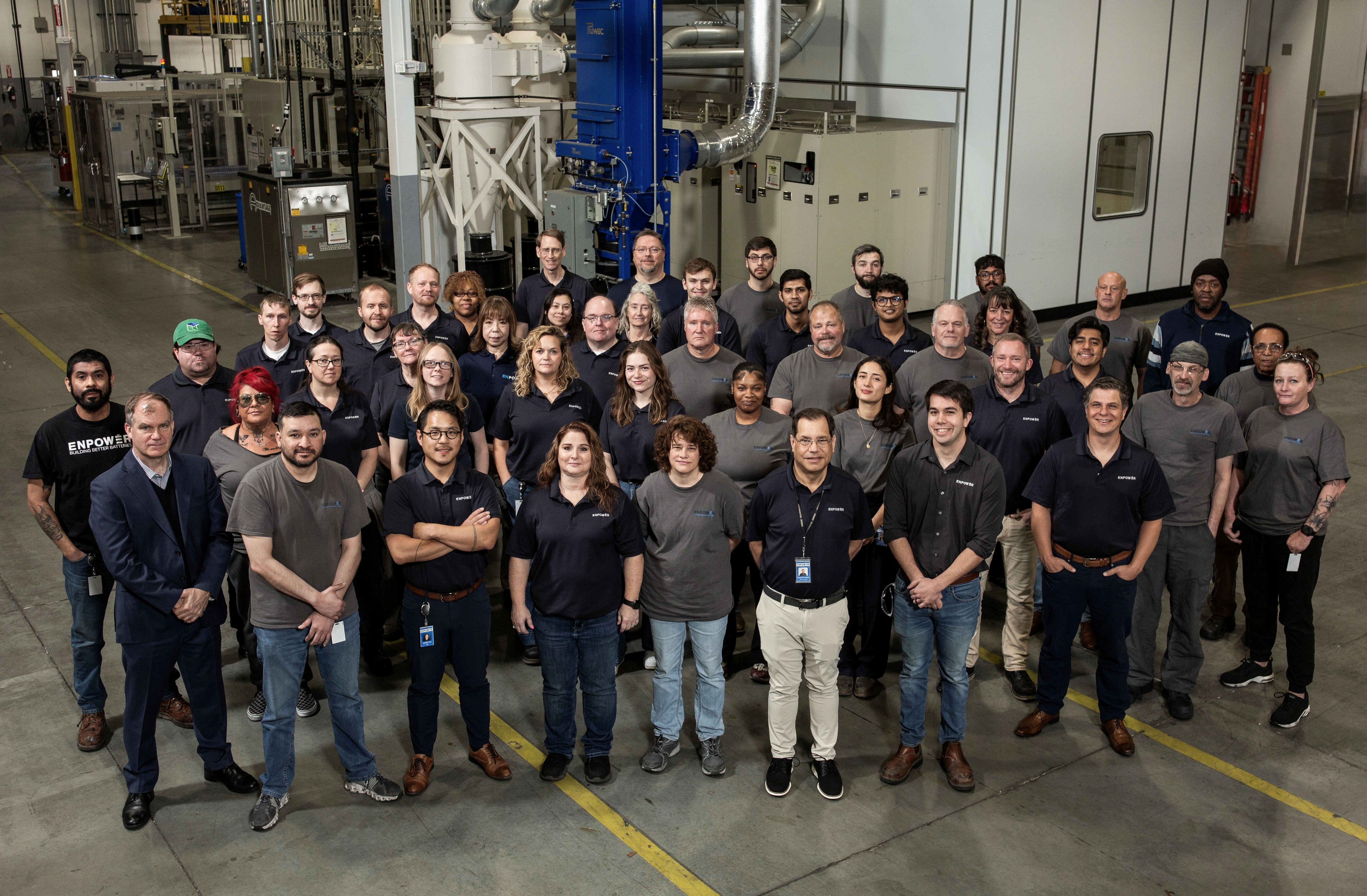 Photo of the EnPower team at the EnPower HQ building with equipment in the background