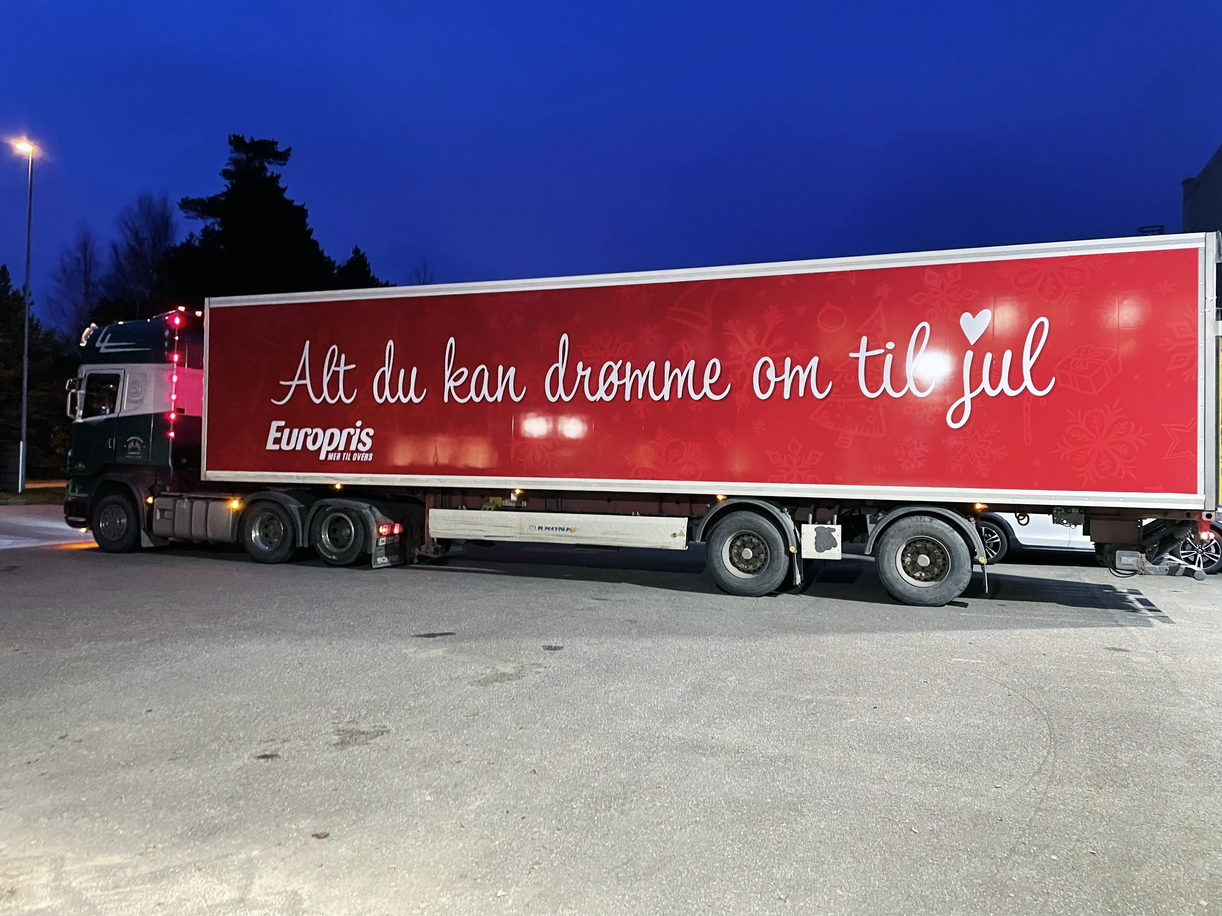Trailer med rød dekor, hvit skrift og Europris-logo med julehilsen, fotografert i skumring