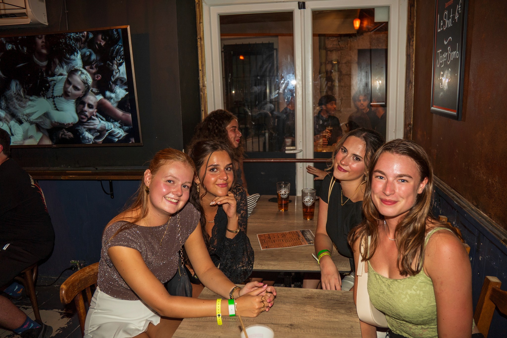 A relaxed group of travelers smiling and talking together inside a cozy bar in Nice during a pub crawl night.