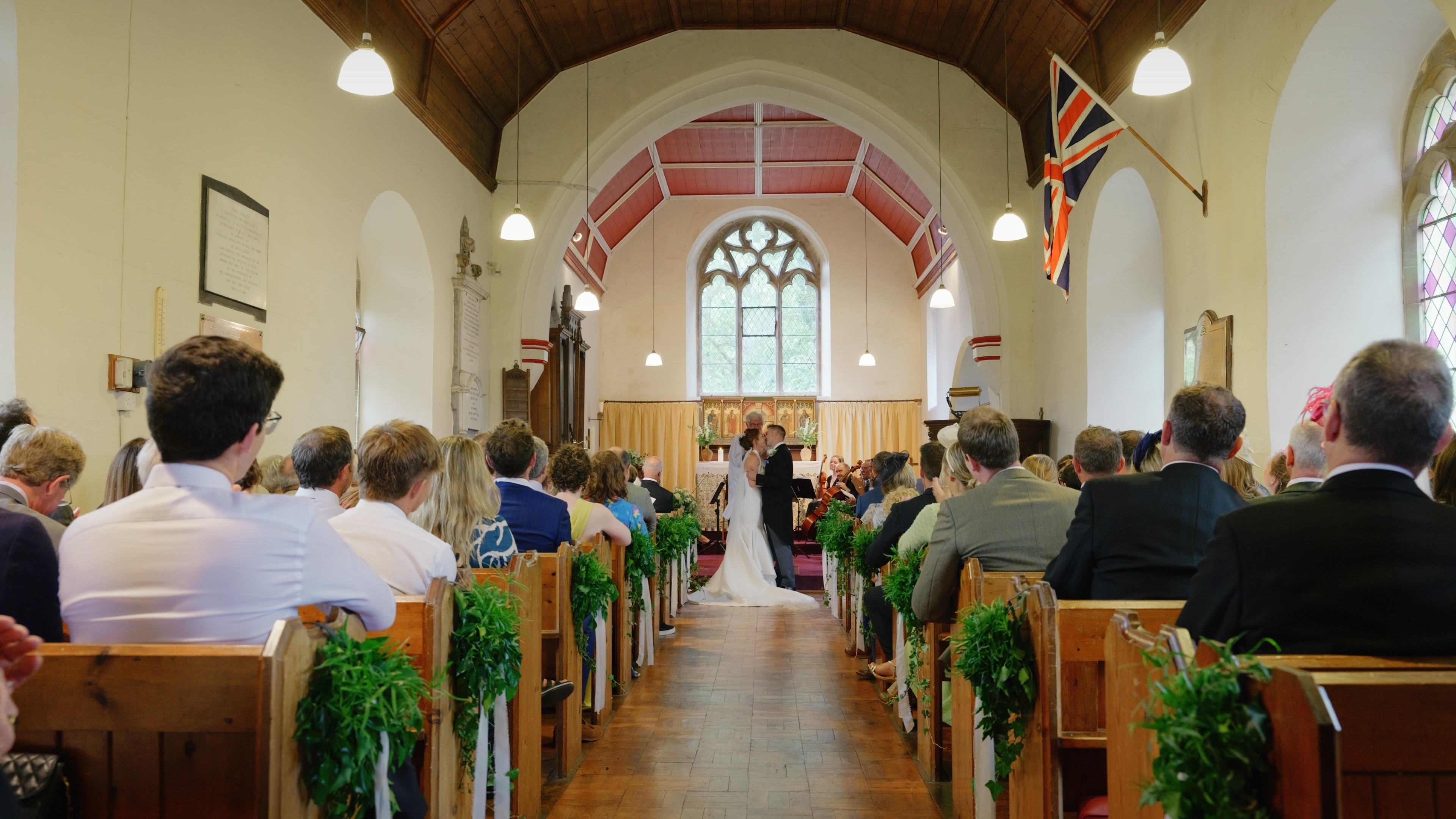 Wide view of a wedding ceremony inside a Lincolnshire church with guests seated and the couple exchanging vows.