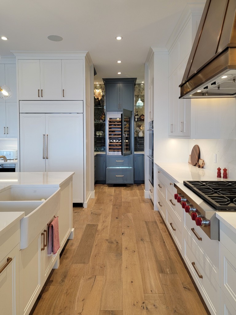 Image of Luxury kitchen design by KHD Homes featuring white cabinets, gas stove, and hardwood floors interior design.