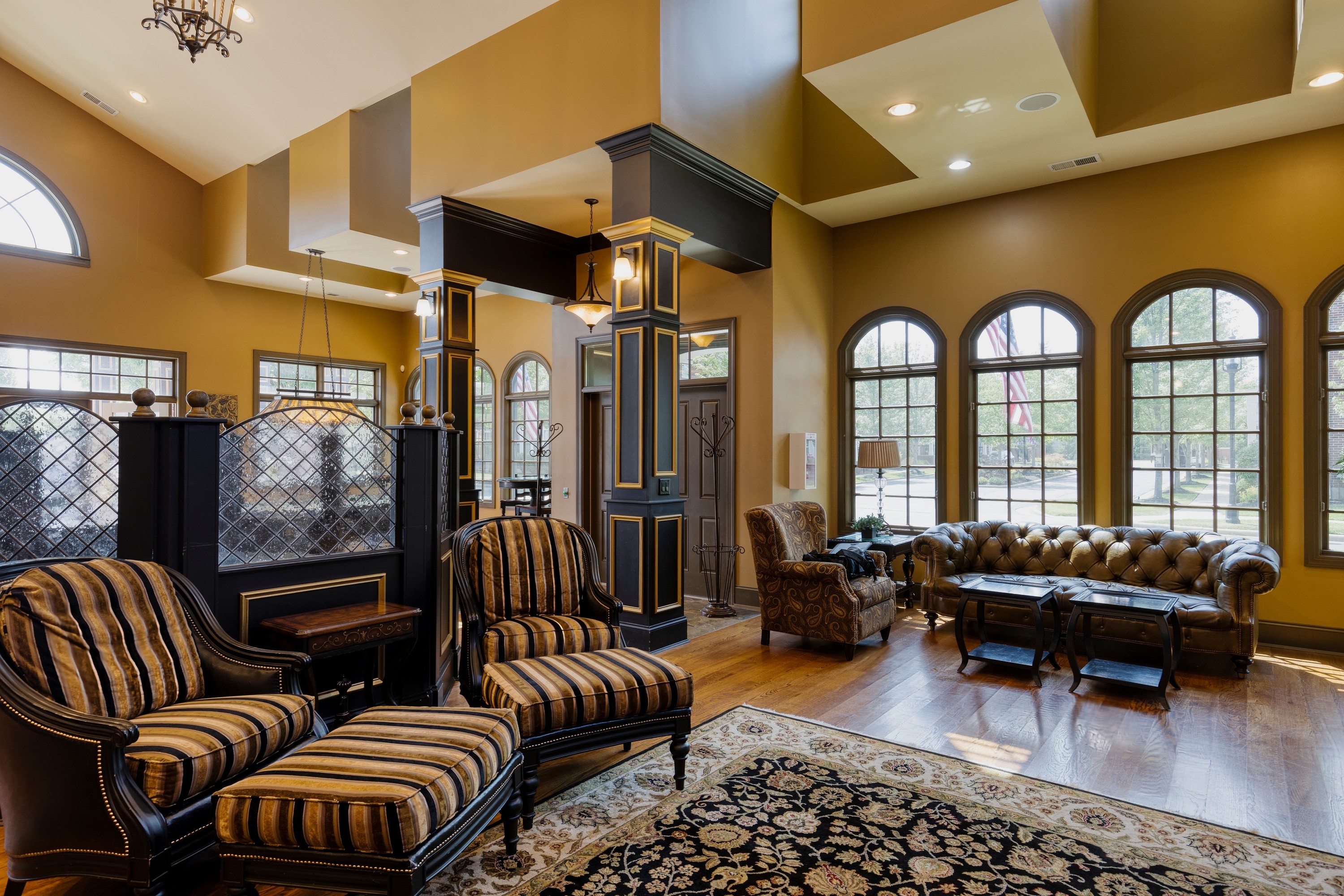 Cozy living room with high ceilings, wooden accents, and large windows illuminating inviting seating areas.