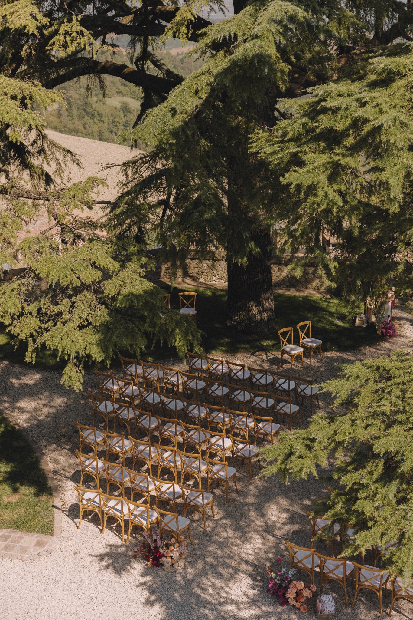 Cerimonia sotto gli alberi di Castello Tabiano, sedie in legno tra il fogliame e la luce naturale filtrata