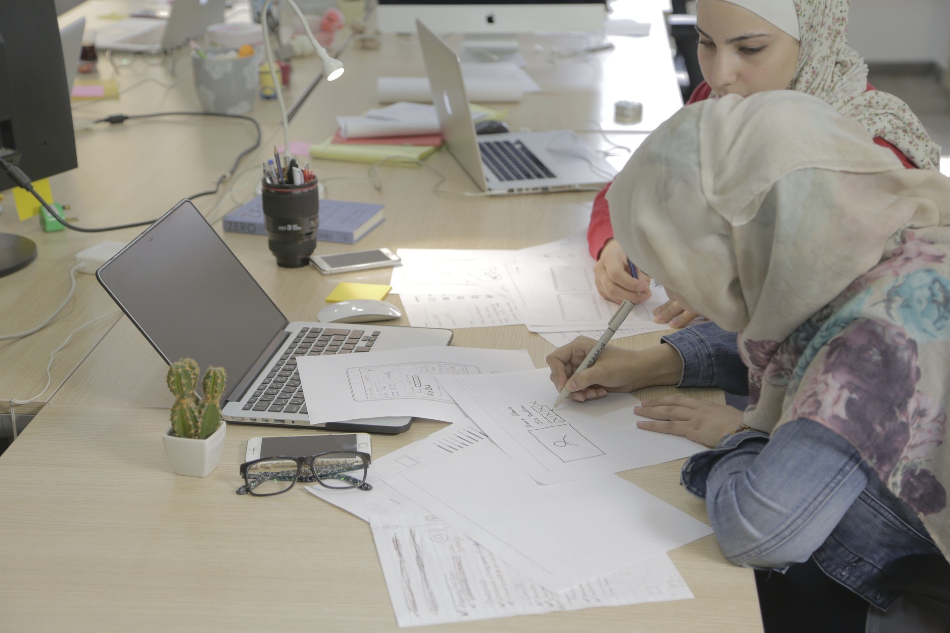 Two designers sketching interface wireframes together at a studio table