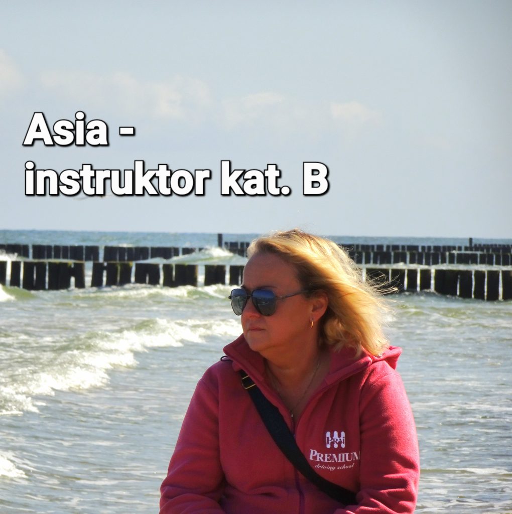 Asia – Instruktorka kat. B siedząca przy plaży, ubrana w bluzę z kapturem.