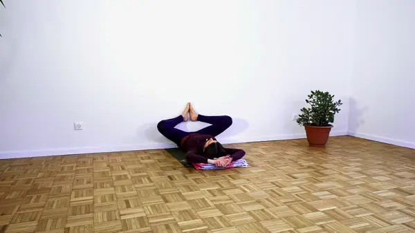 Woman in a supported seated yoga pose using the wall – postnatal yoga class to release tension and calm the nervous system through restorative leg positions