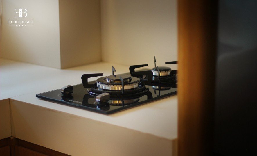 Close-up of the modern two-burner gas stovetop on the white kitchen counter within the Echo Beach Suite, a luxury accommodation option in Canggu, Bali.