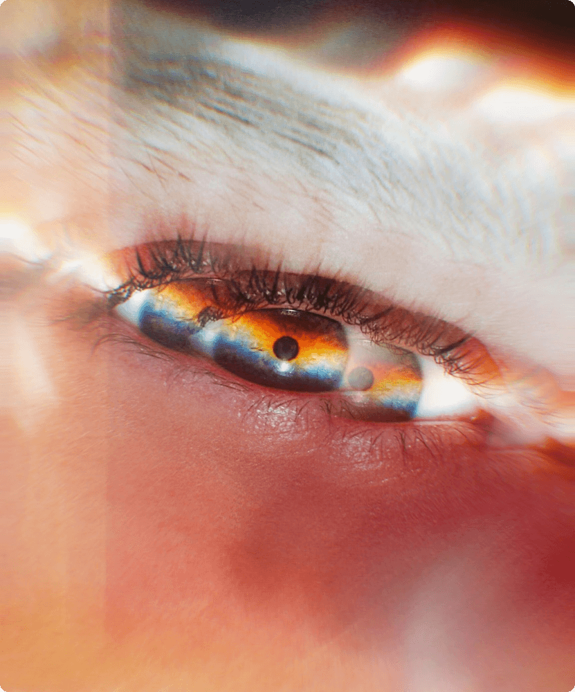  An extreme close-up of a human eye with a dreamlike, prismatic light effect creating rainbow colors across the iris and lens flare around the edges