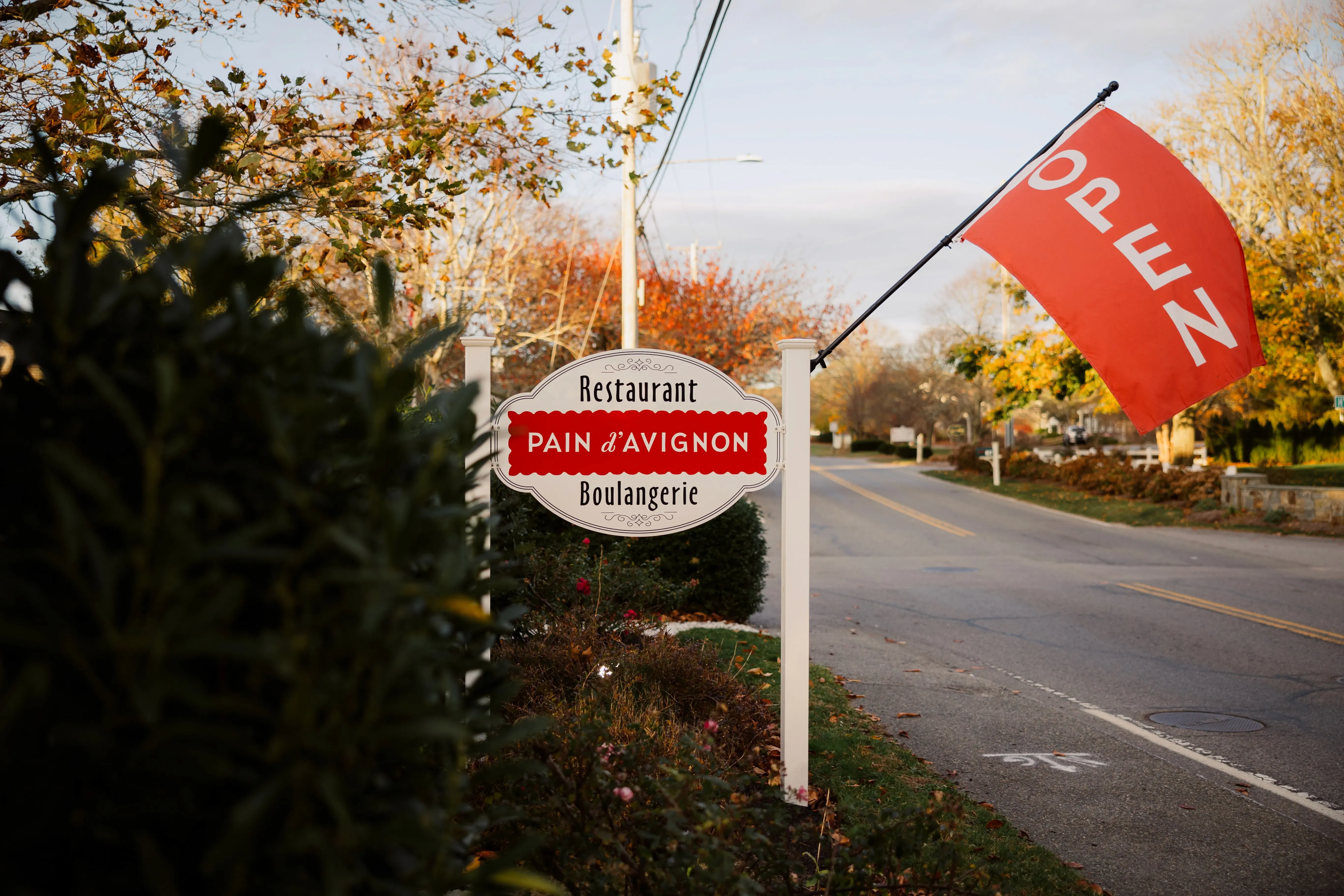 ain d'Avignon Chatham roadside sign — Restaurant · Boulangerie with red Open flag, Cape Cod
