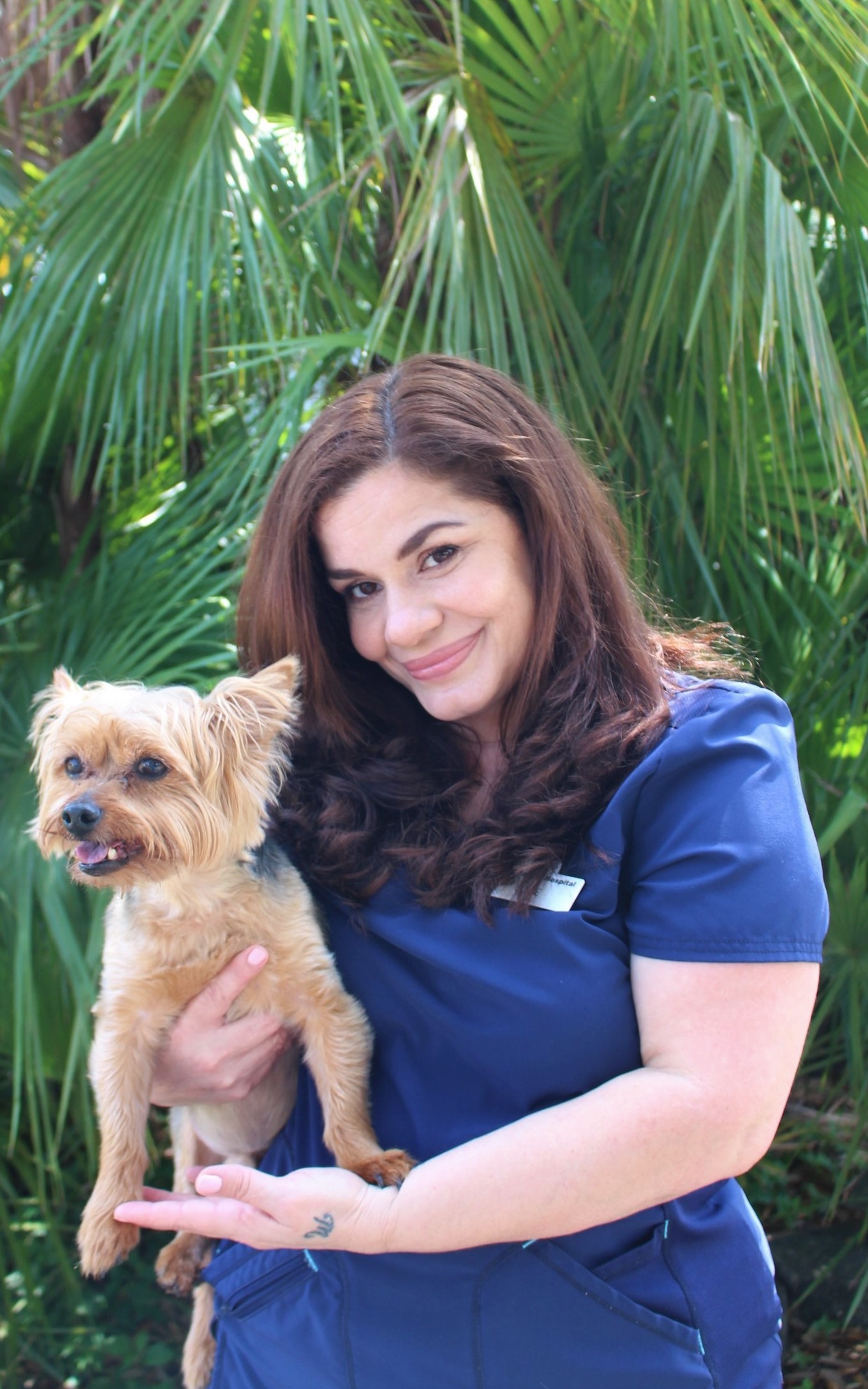 elyse holding a yorkie in front of greenery