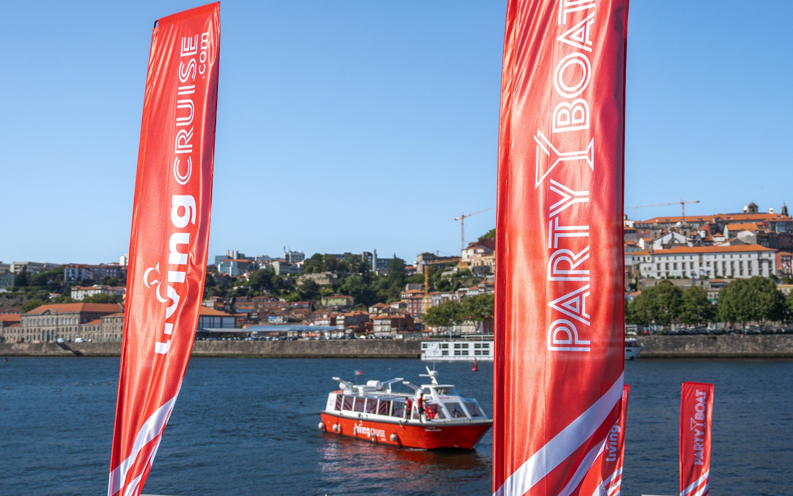 Barco festa no rio Douro com a cidade do Porto como pano de fundo.