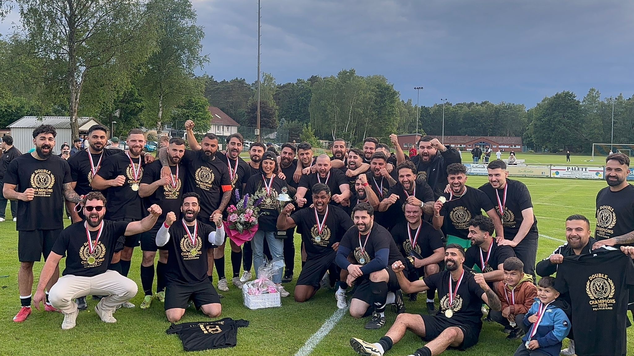Die Fußballmannschaft von United Celle jubelt ausgelassen gemeinsam mit einer Urkunde auf dem Rasen.