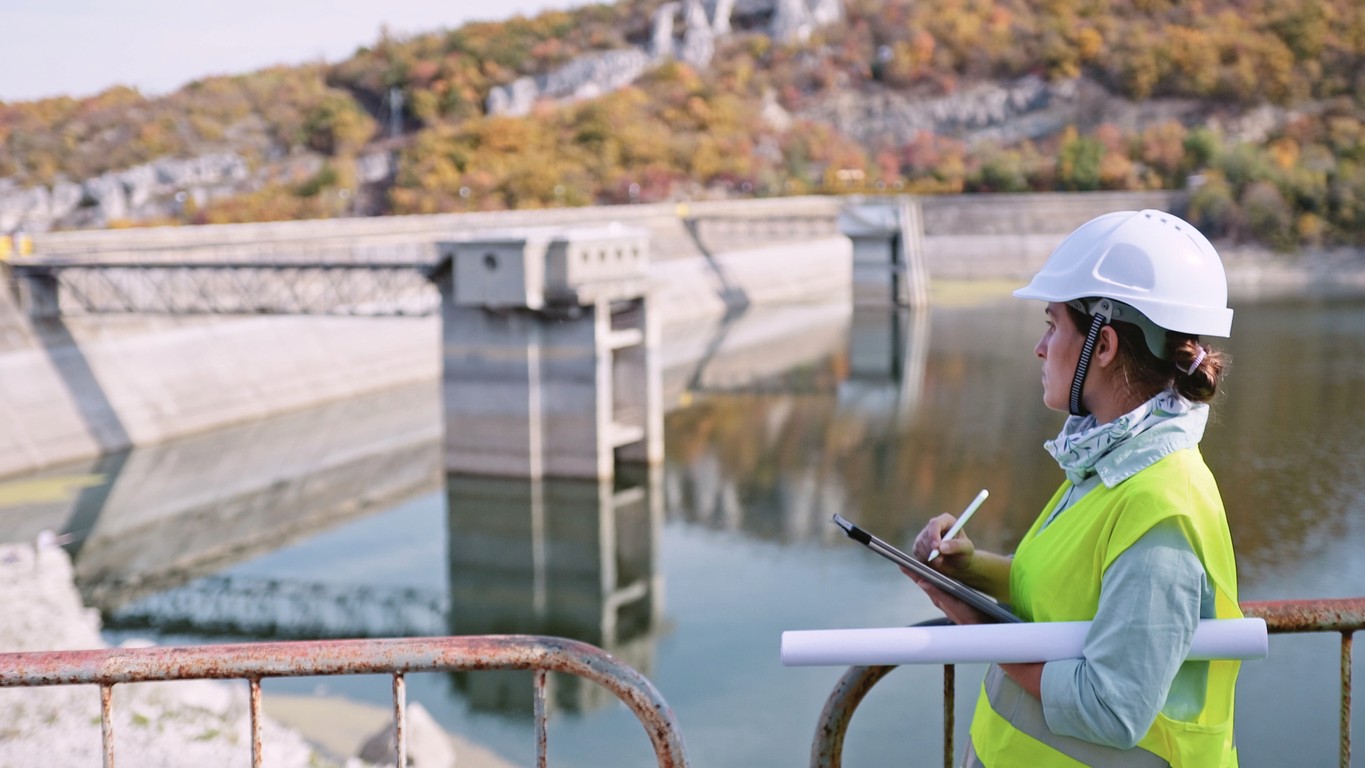 A woman with a hardhat overseeing a dam facility