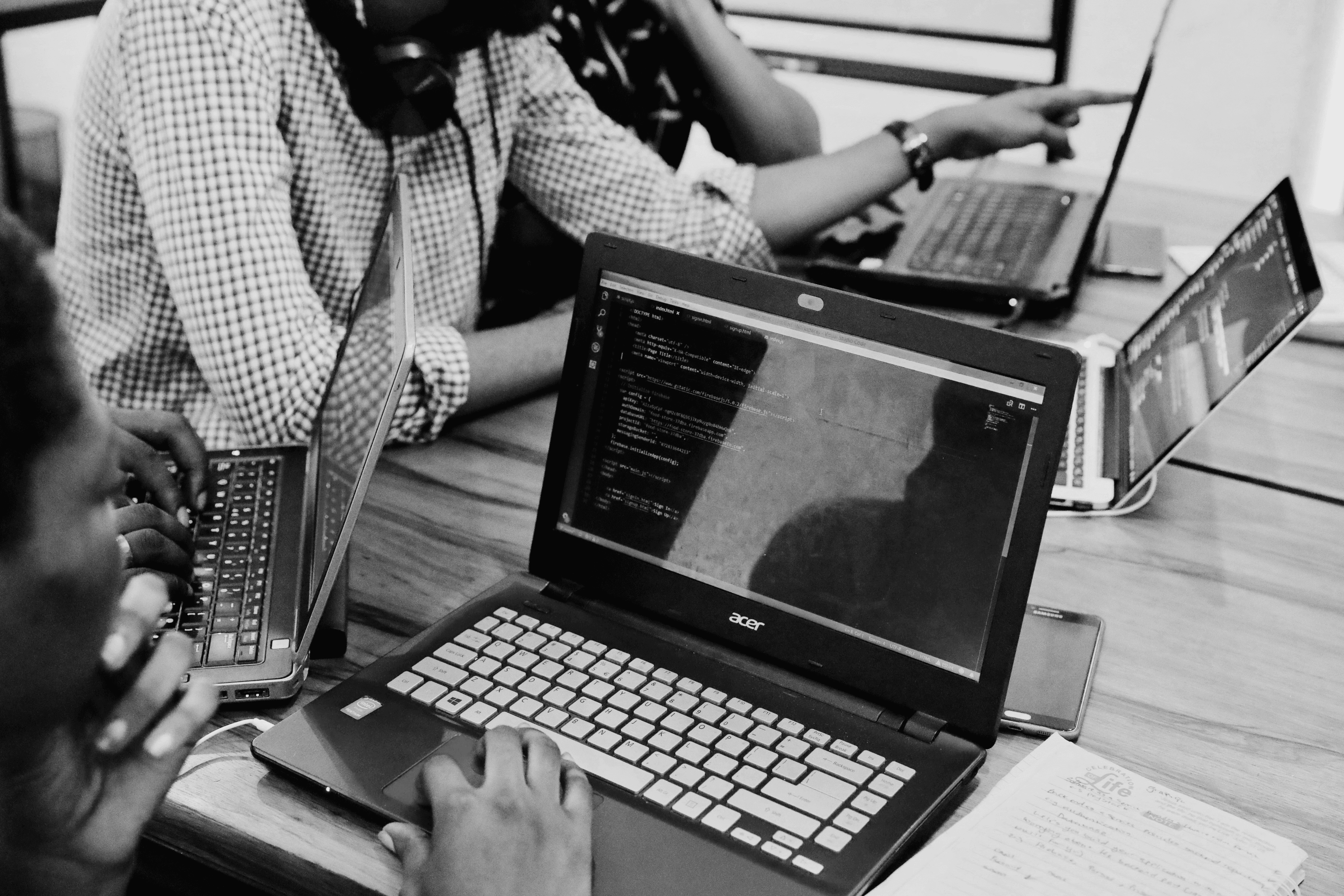 Four people coding on their laptops and collaborating.