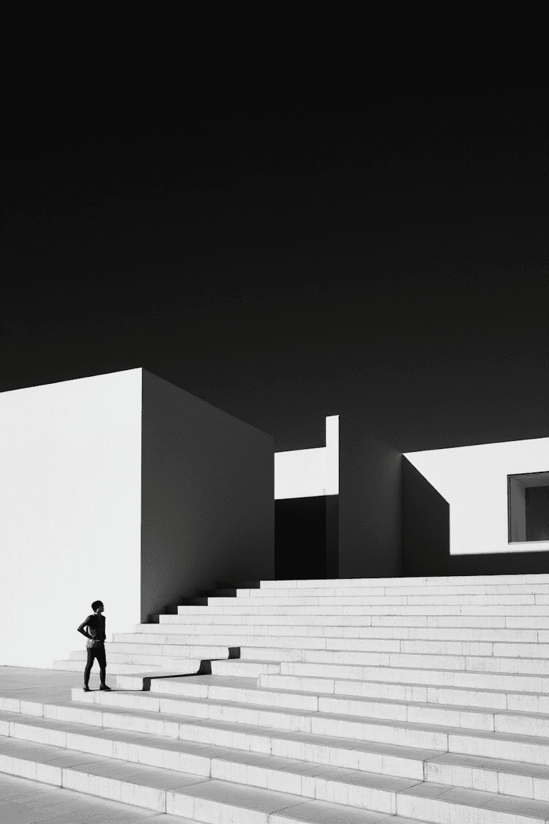 A black and white photo of a person descending a staircase, capturing their silhouette against the light.