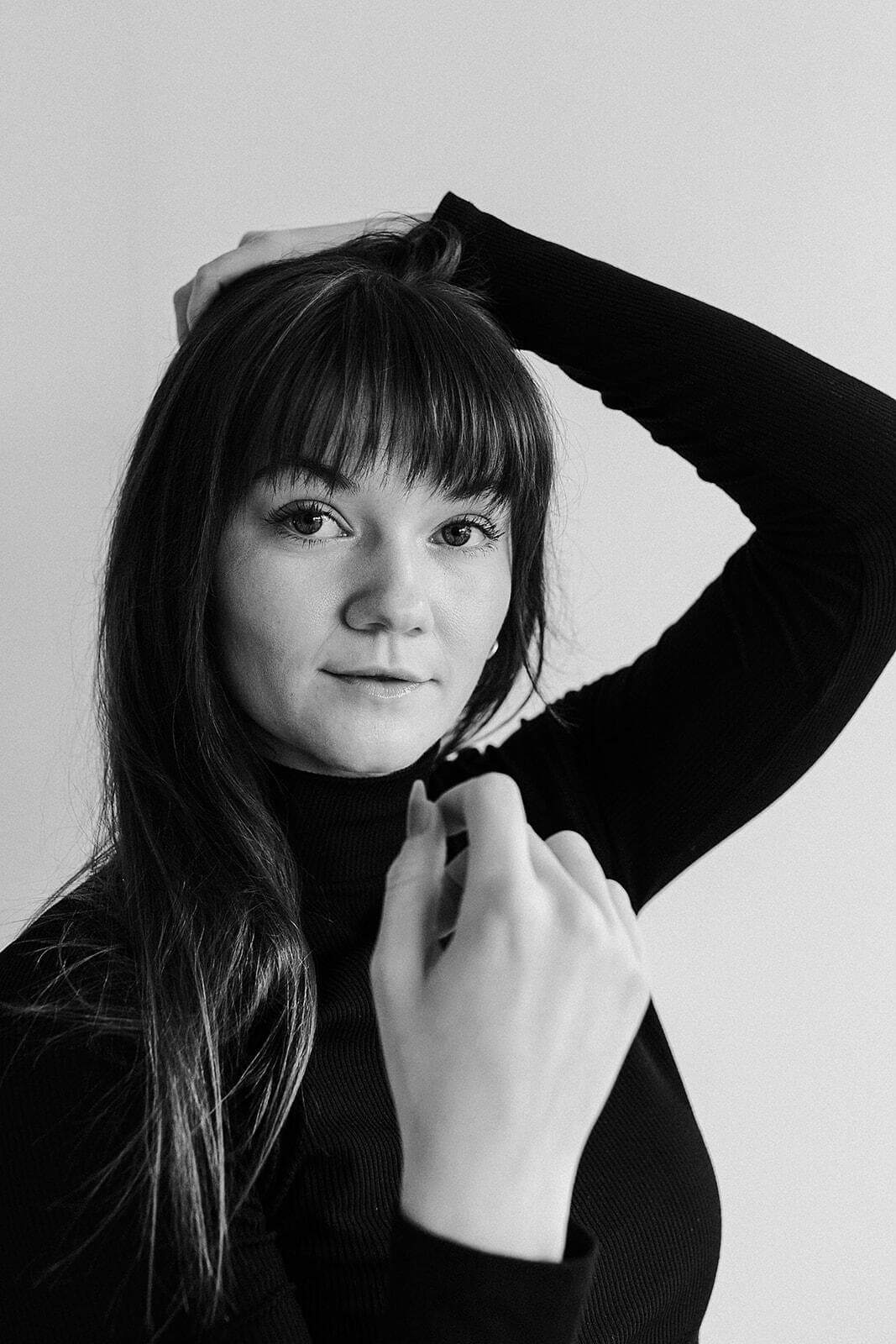 A black-and-white portrait of a model posing gracefully at Revelator Studio in Shreveport, showcasing the natural light and minimalist backdrop ideal for professional photography sessions.