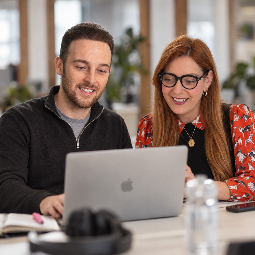 Two Climbing Trees team members reviewing work on a laptop