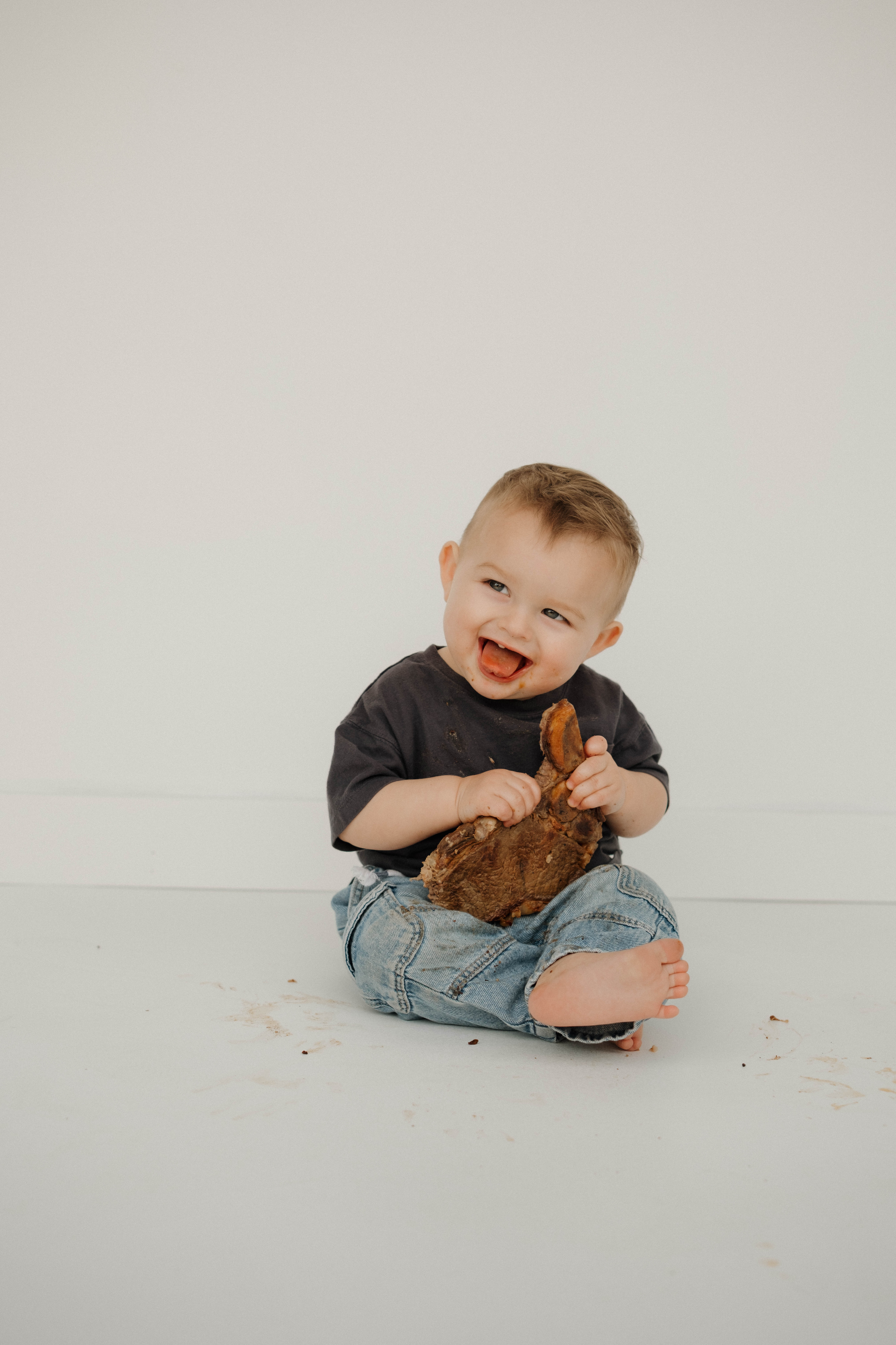 Lifestyle family photoshoot in Arizona, showing a heartwarming scene of a father tossing his baby in the air as the mother lovingly holds their other infant.