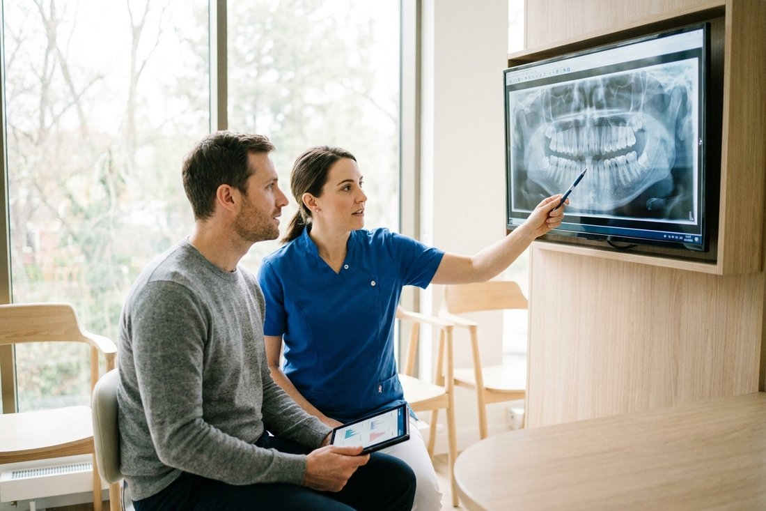 Dentist and patient reviewing a panoramic X-ray while discussing extraction cost