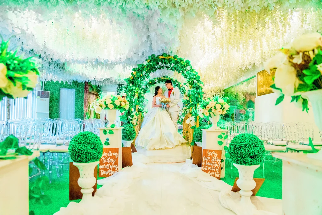 Newlyweds on the garden stage under white wisteria at Celestia Hall, Stalla Suites Events Place