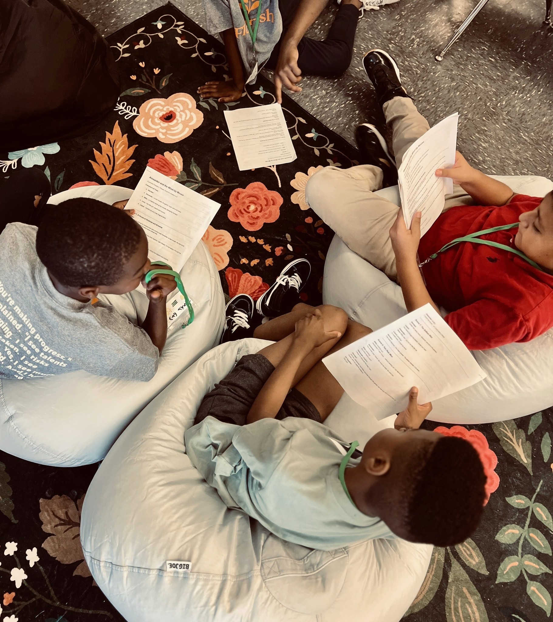 Aerial view of four people gathered around a table with drinks and snacks, engaged in conversation and sharing.