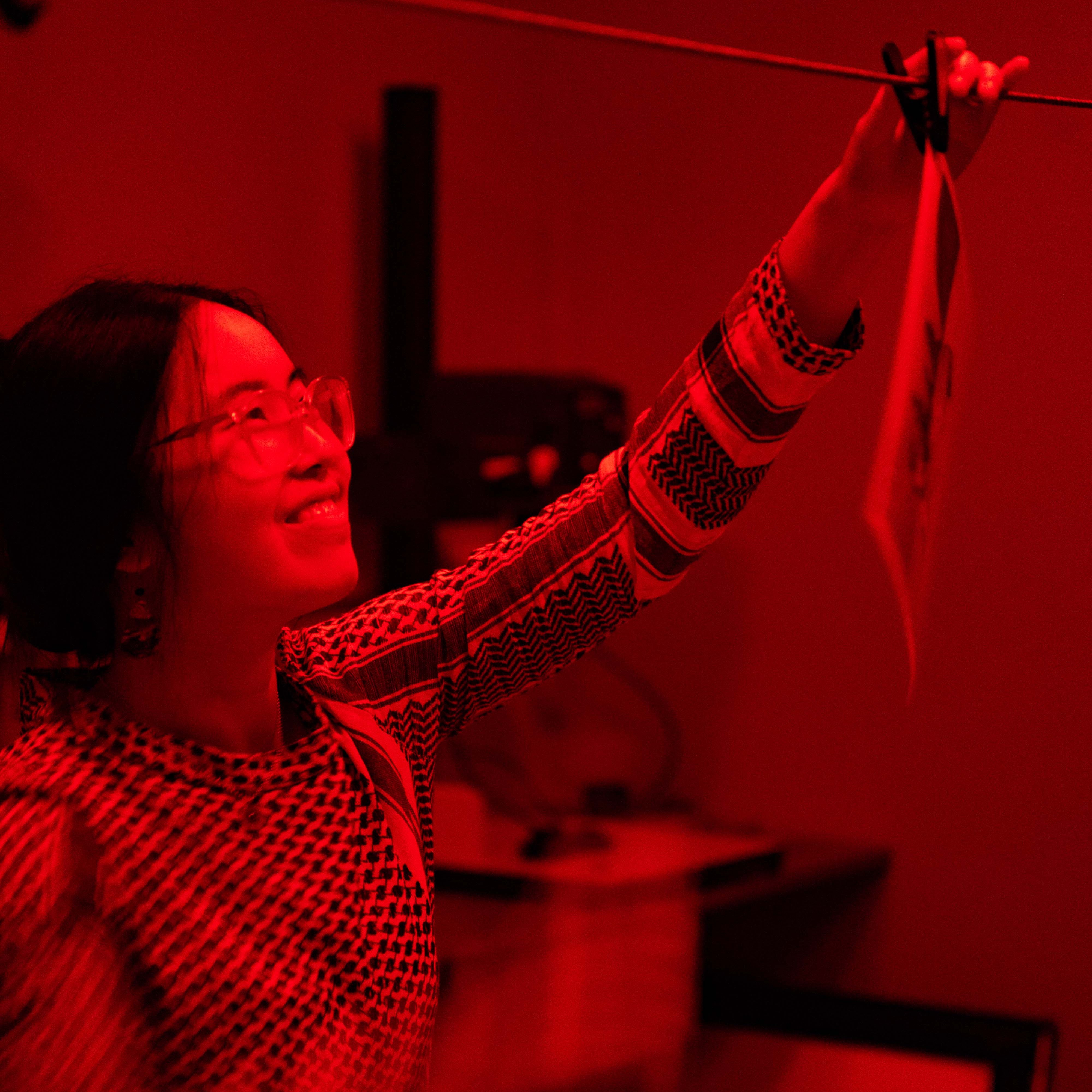Person hanging print in a darkroom safelight