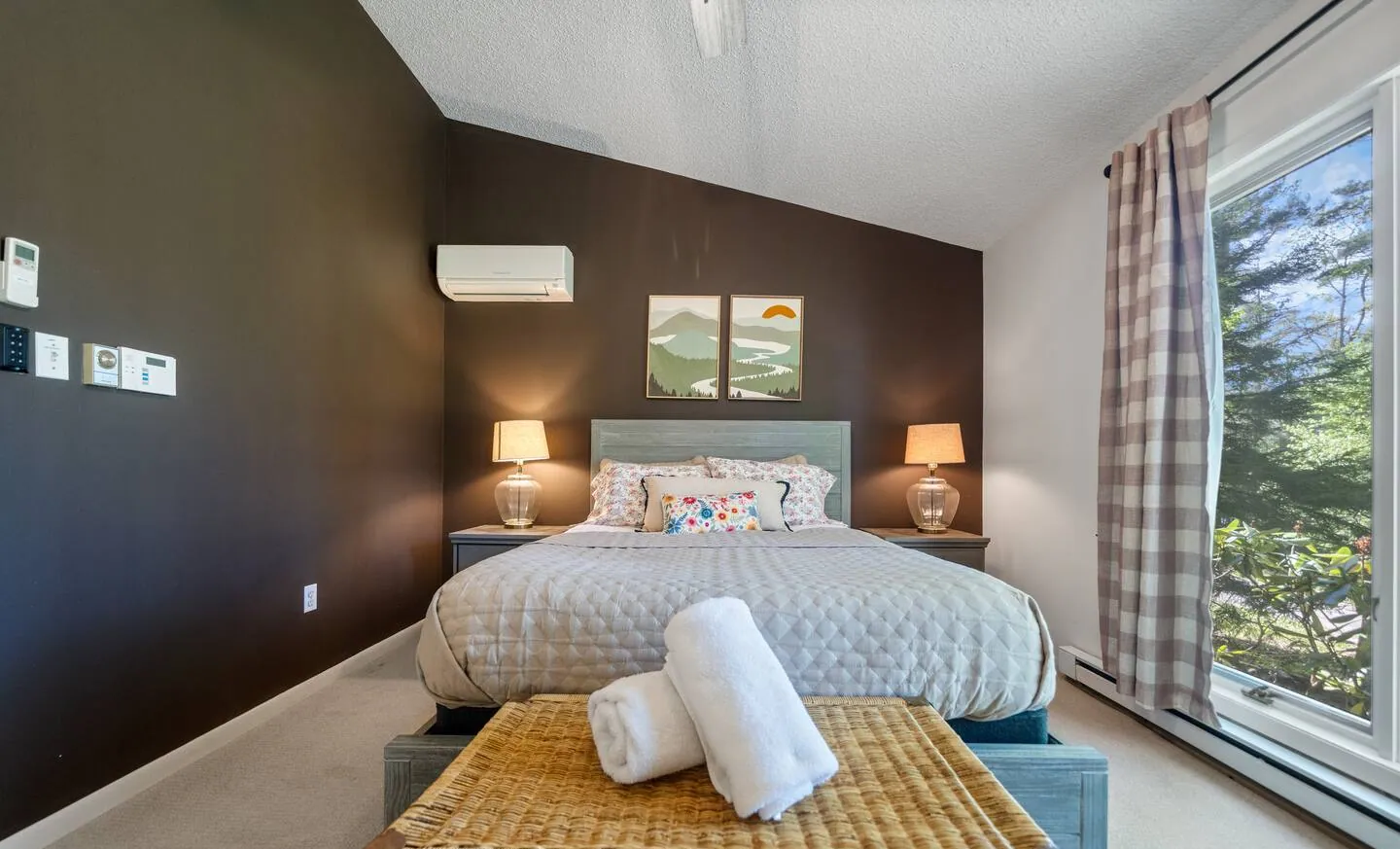 Queen bed with white linens, wicker bench and plaid curtains at Lake Front, Lake Naomi