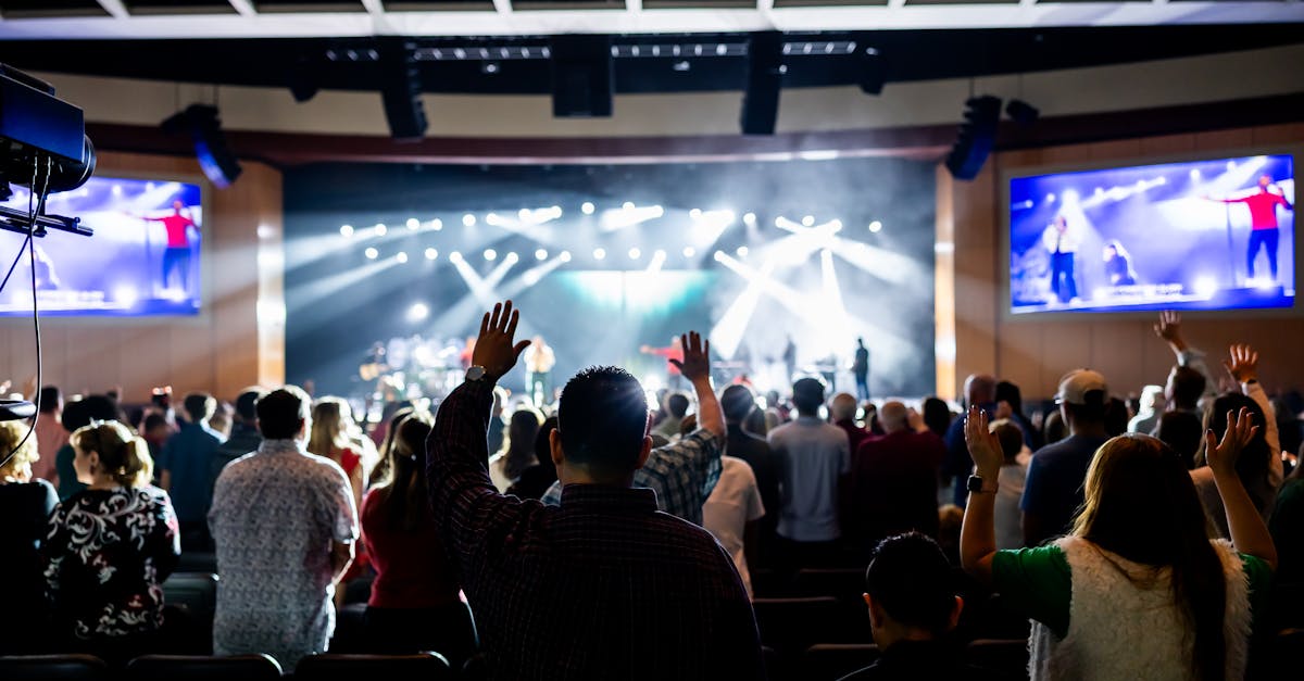 A lively crowd enjoys a live concert in a modern theater setting, hands raised in excitement.