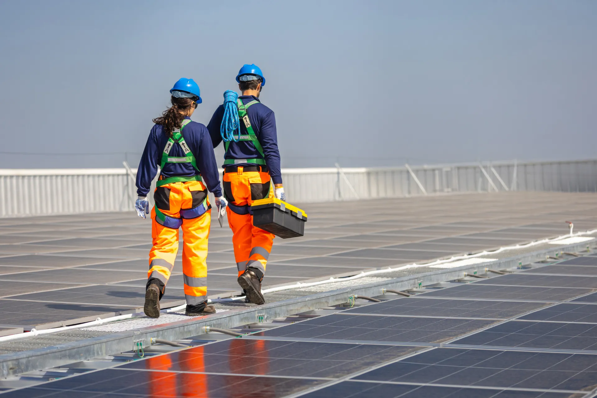 Zwei Installateure welche auf einem Falchdach eine PV-Anlage installieren.
