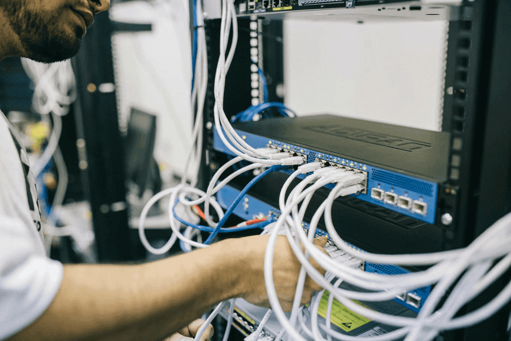 Technician patching Ethernet cables into a switch in an open network rack